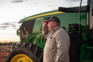 agriculture photography of farmer next to tractor on land with sunset