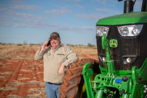agriculture photography of farmer next to john deere tractor on phone